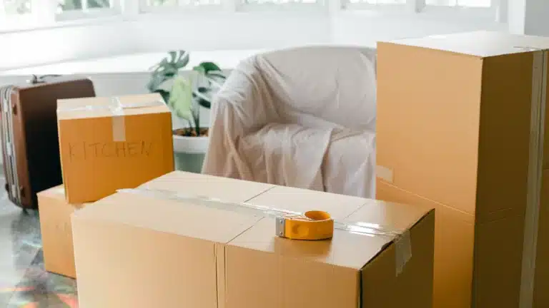 Cartons de déménagement et fauteuil protégé dans une pièce lumineuse